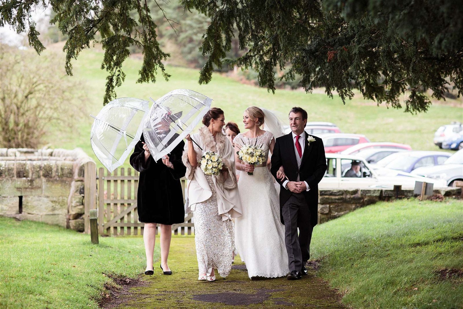 Sheltering from the rain, the bridesmaids are waiting for their bride at All Saints Church in Sandon by Stafford Recommended Wedding Photographer Stuart James